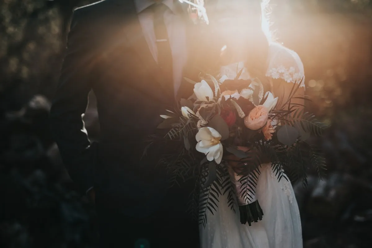 Bride and groom with bouquet at golden hour wedding ceremony